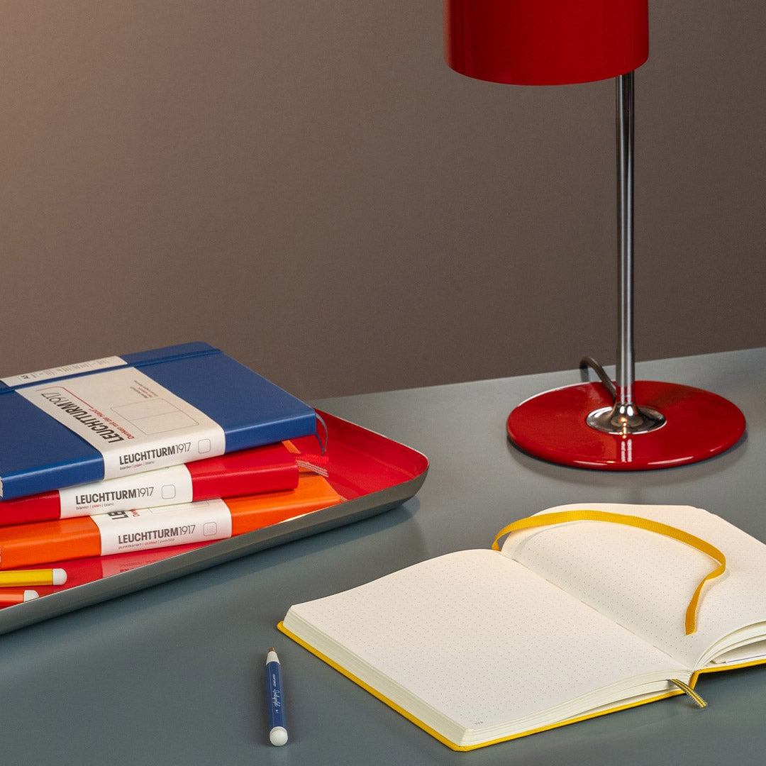 Leuchtturm Colours 2025 op een bureau - Indigo, Sunflower, Cherry en Pumpkin